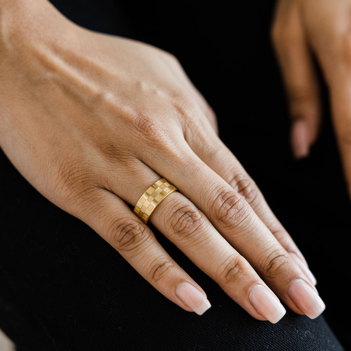 Hand wearing the gold Queen’s Ring with wide checkered band