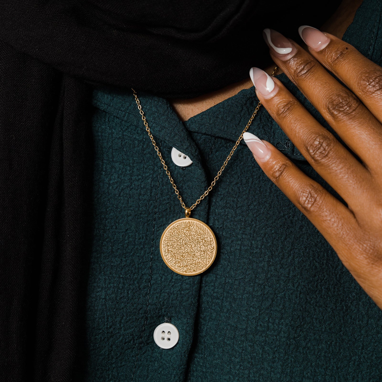 Close up of the gold Ayatul Kursi Necklace as worn by the model.
