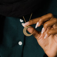 The Ayatul Kursi Crescent Necklace in a polished silver finish, showcasing a crescent pendant adorned with detailed Arabic inscriptions, hanging from a fine silver chain.