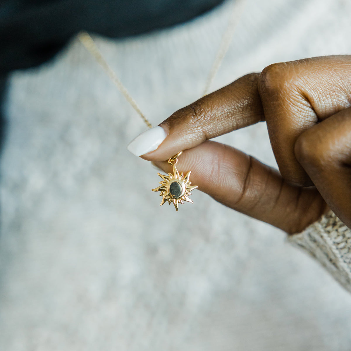 Close up of the gold pendant as the model lifts the chain of the gold Arizona Sunrise Necklace