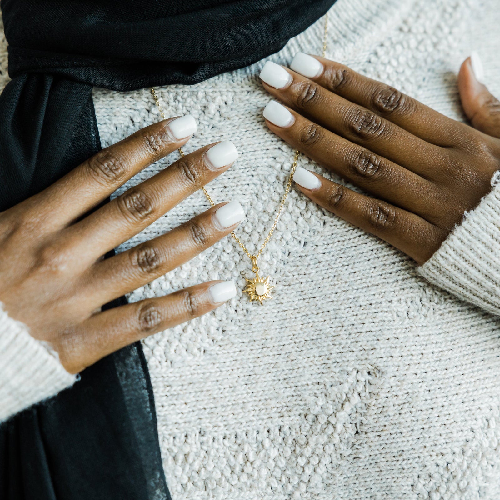 Close up of the gold Sunrise Necklace against the white fabric of the model's clothing.