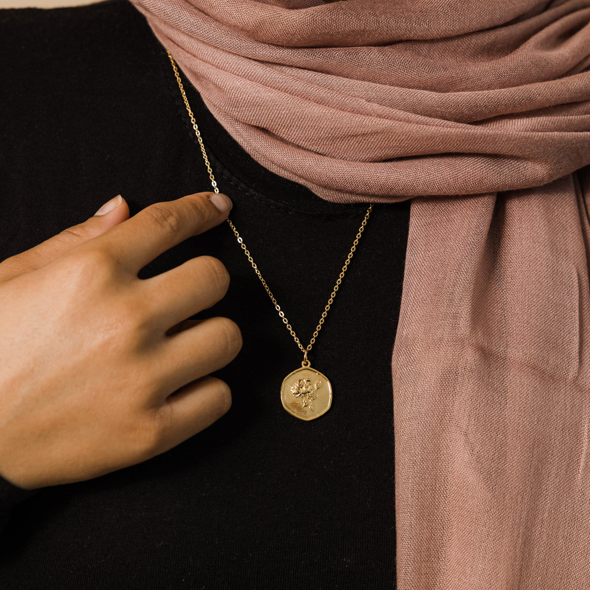 Close up of the October | Birth Flower Pendant against the black fabric of the model's clothing.