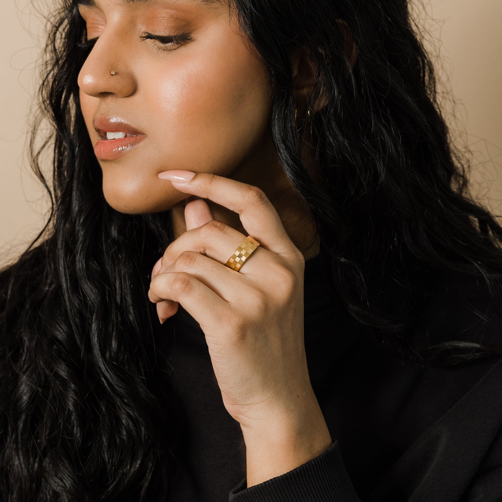Close-up of woman wearing the Queen’s Ring, gold checkered band styled on her finger
