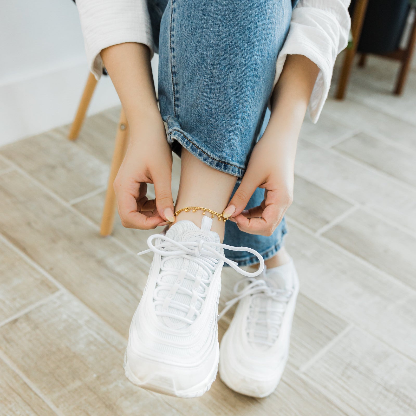 A model wearing the 18K gold-plated Dangling Dotted Anklet. The anklet rests gracefully on her ankle, highlighting the dangling ball-shaped charms against her skin.