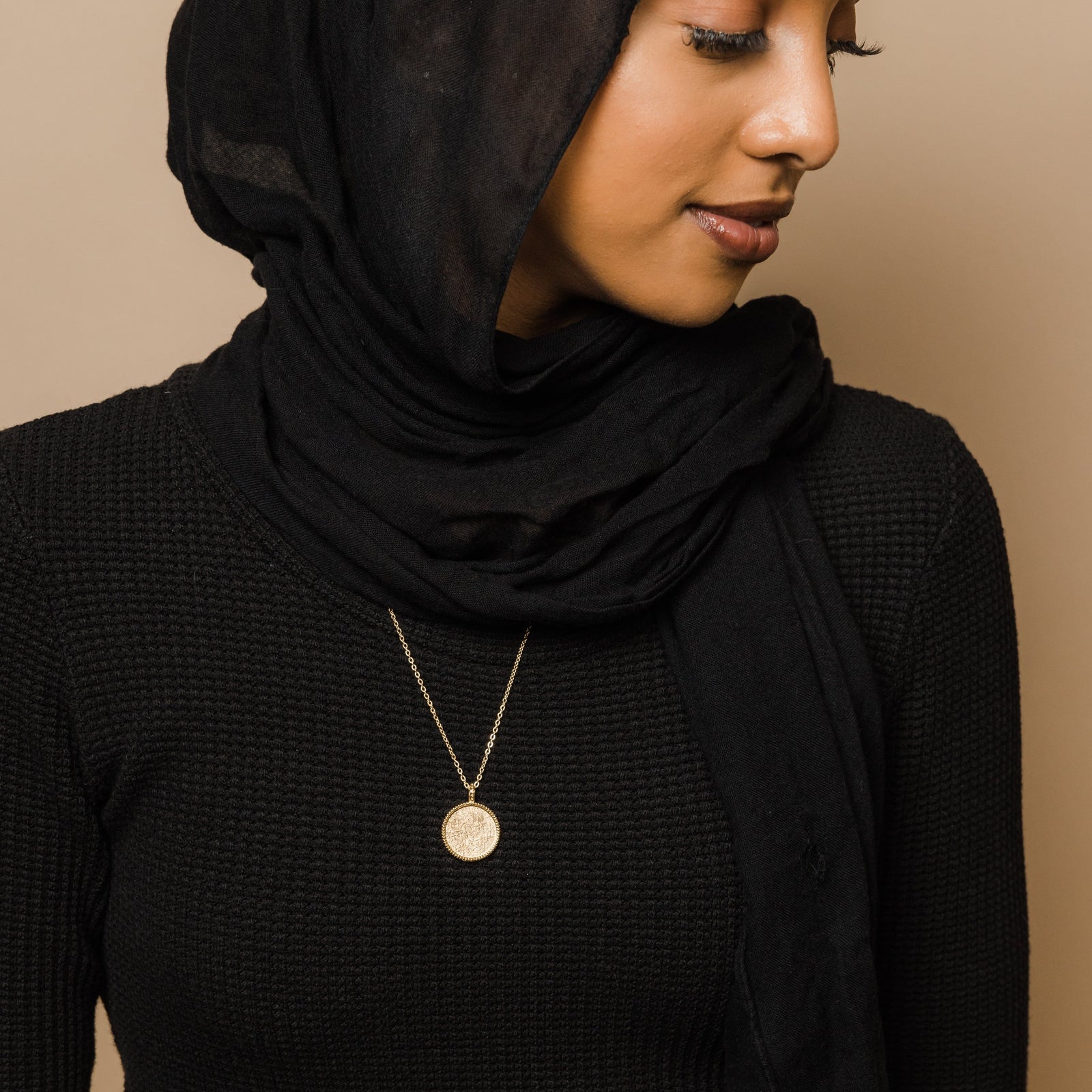 Photo of the model wearing the gold Patience Token Necklace.