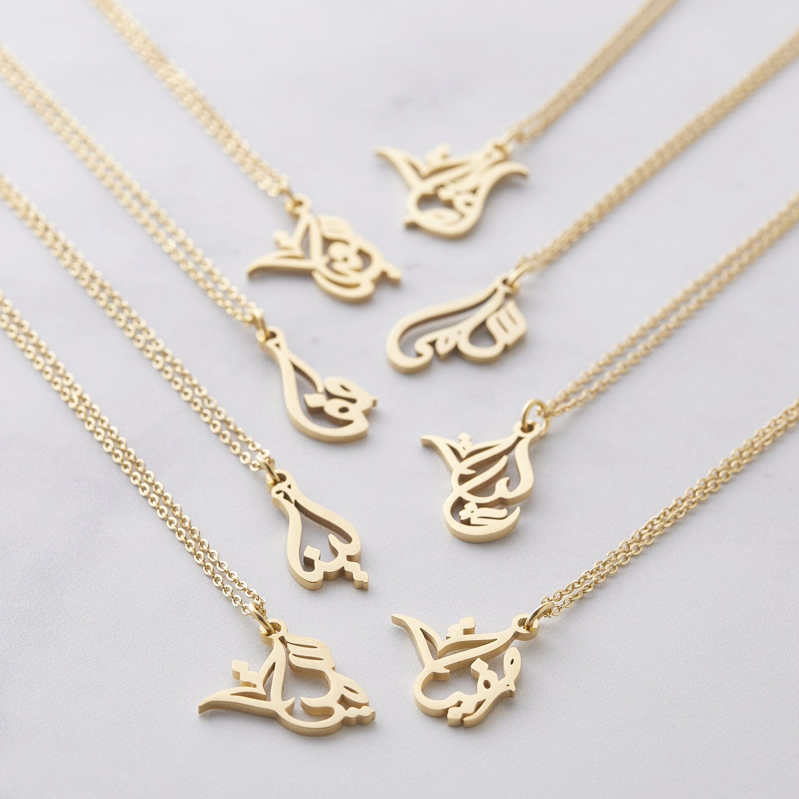 Photo of the gold Ready Calligraphy Name Necklace in 8 different variants.