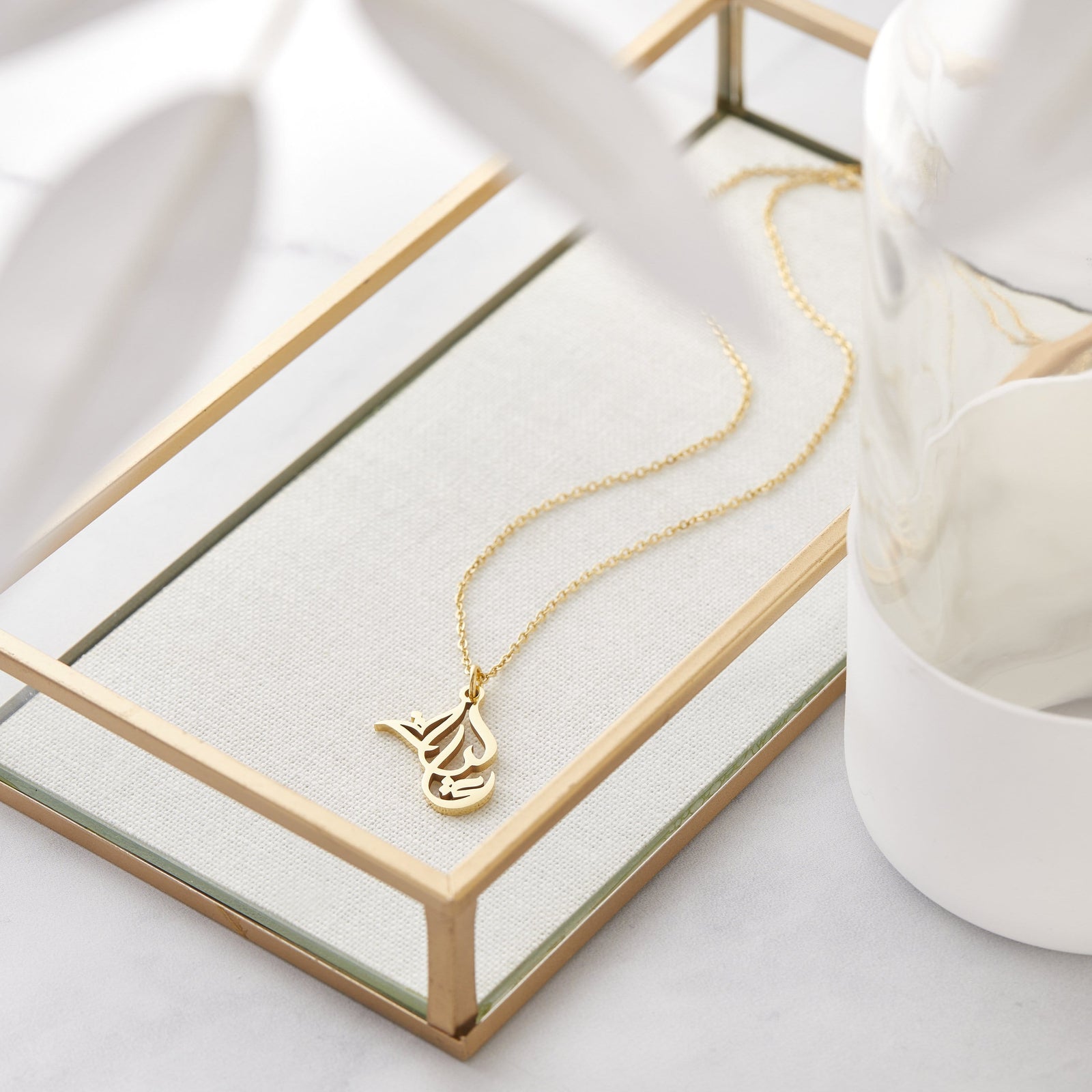 Close up of the gold Ready Calligraphy Name Necklace - Aaliyah on a jewelry frame