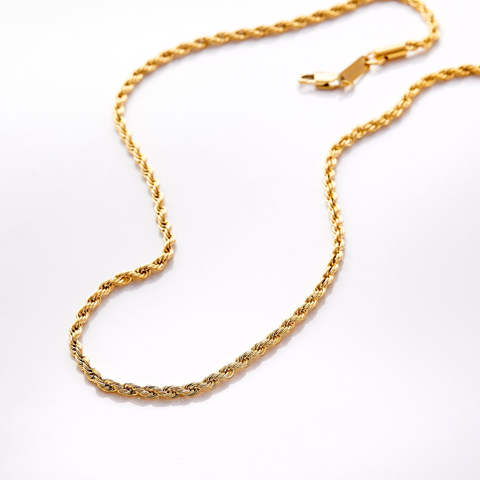 Gold rope chain necklace with lobster clasp displayed on a white background, styled in a gentle curve.