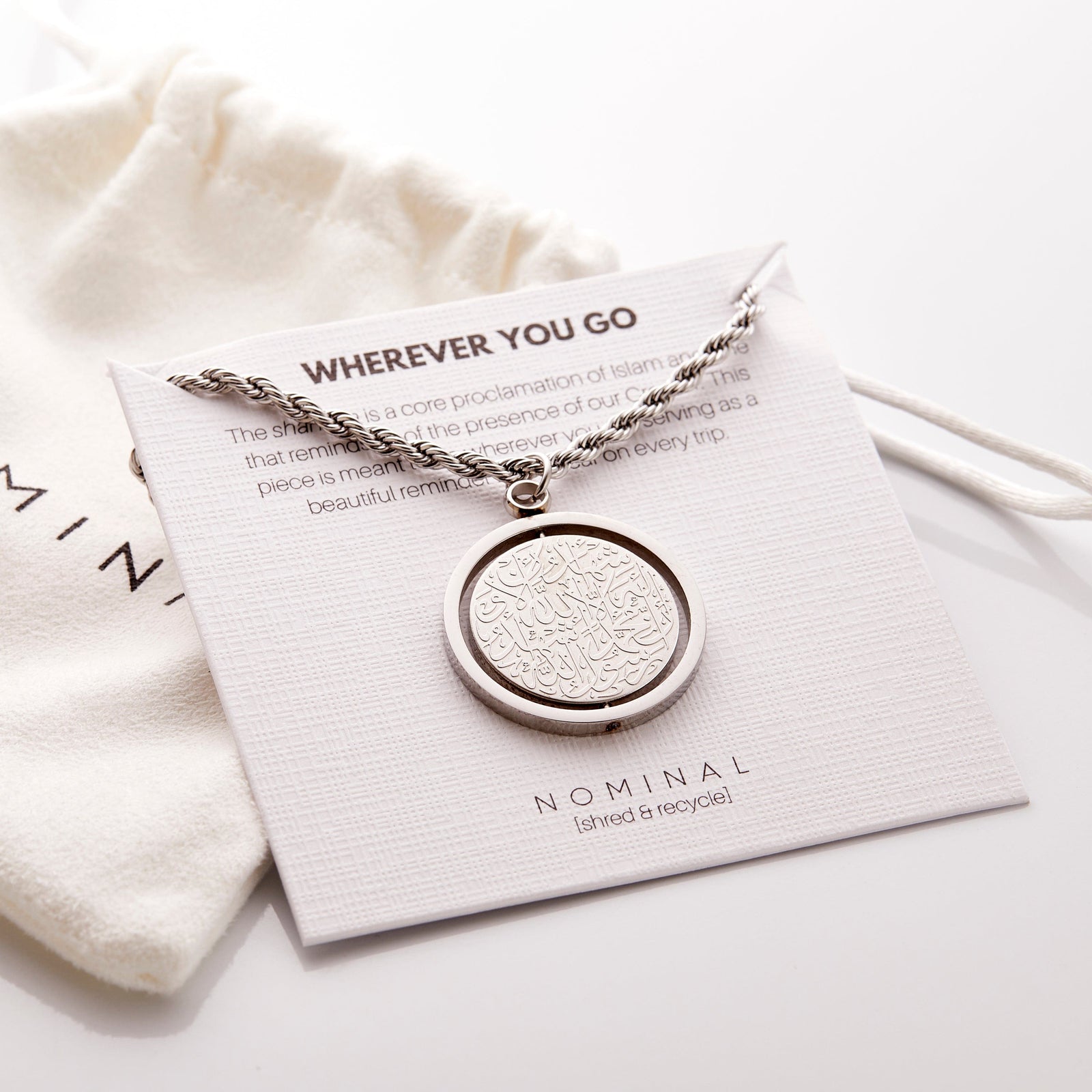 Silver Shahada car hanger displayed on a Nominal card reading “Wherever You Go” with pouch in the background.