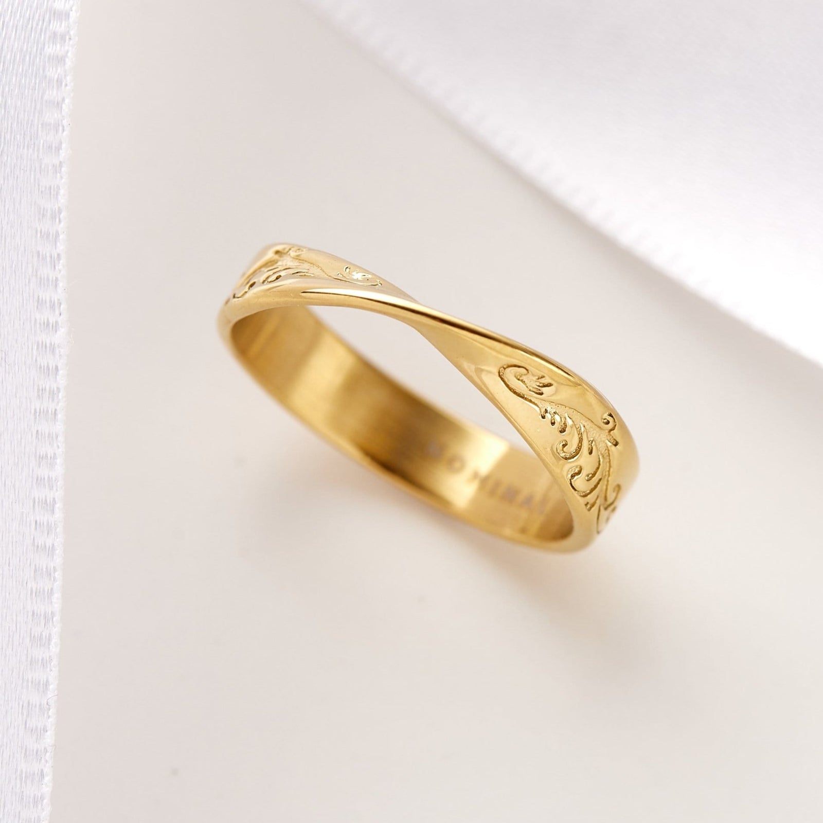 Close-up angled view of the gold tidal wave ring showing engravings