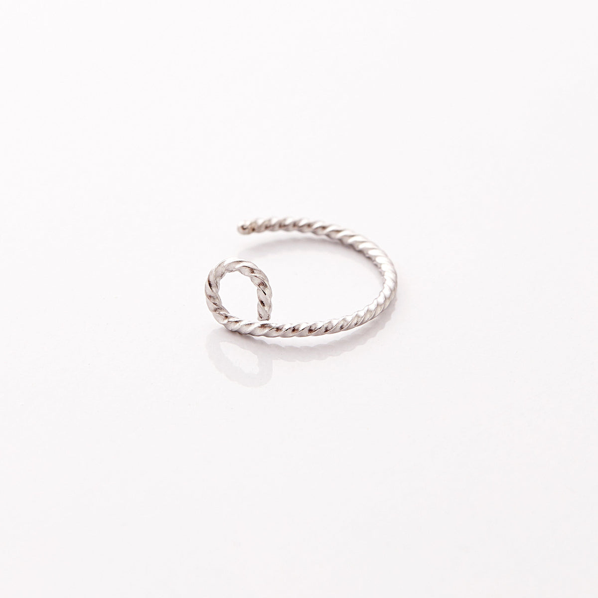 Photo of a silver nose hoop marked with a spiraling patter against a light background.