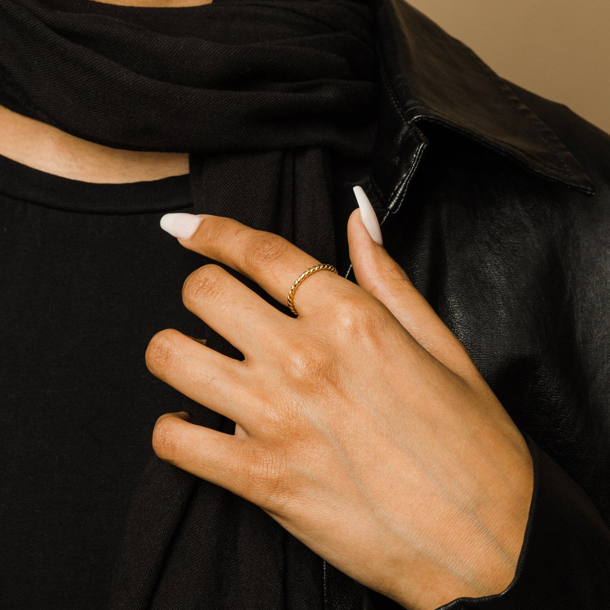 Woman’s hand wearing a gold twist ring on her finger.