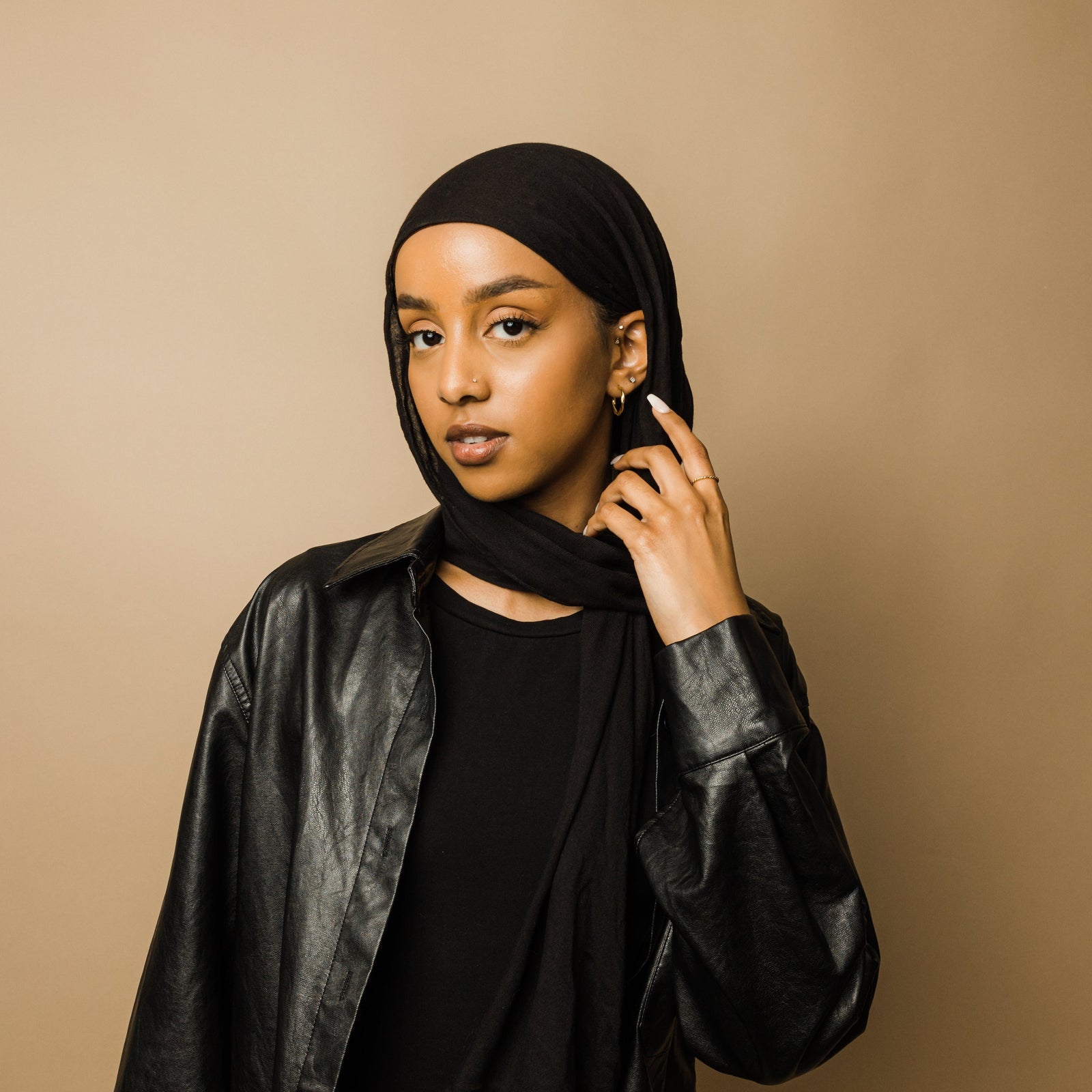 Woman in a black scarf and leather jacket wearing the gold twist ring.