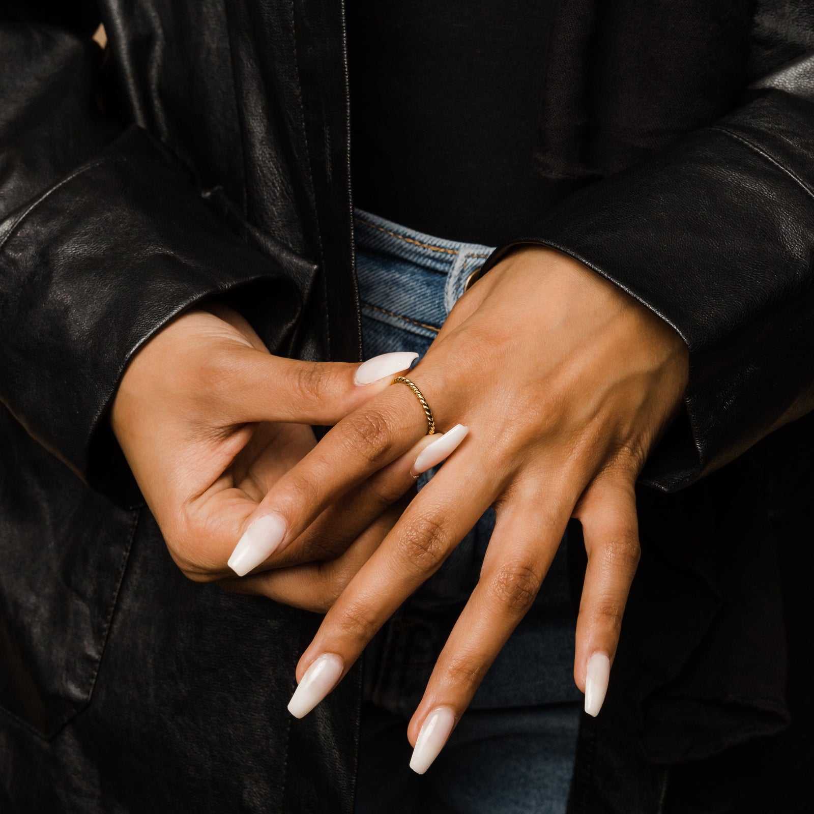 Woman adjusting the gold twist ring on her finger.