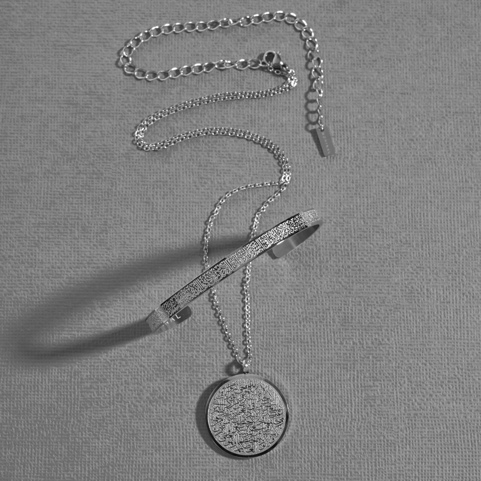 Photo of the silver Ayatul Kursi necklace and Ayatul Kursi Cuff.