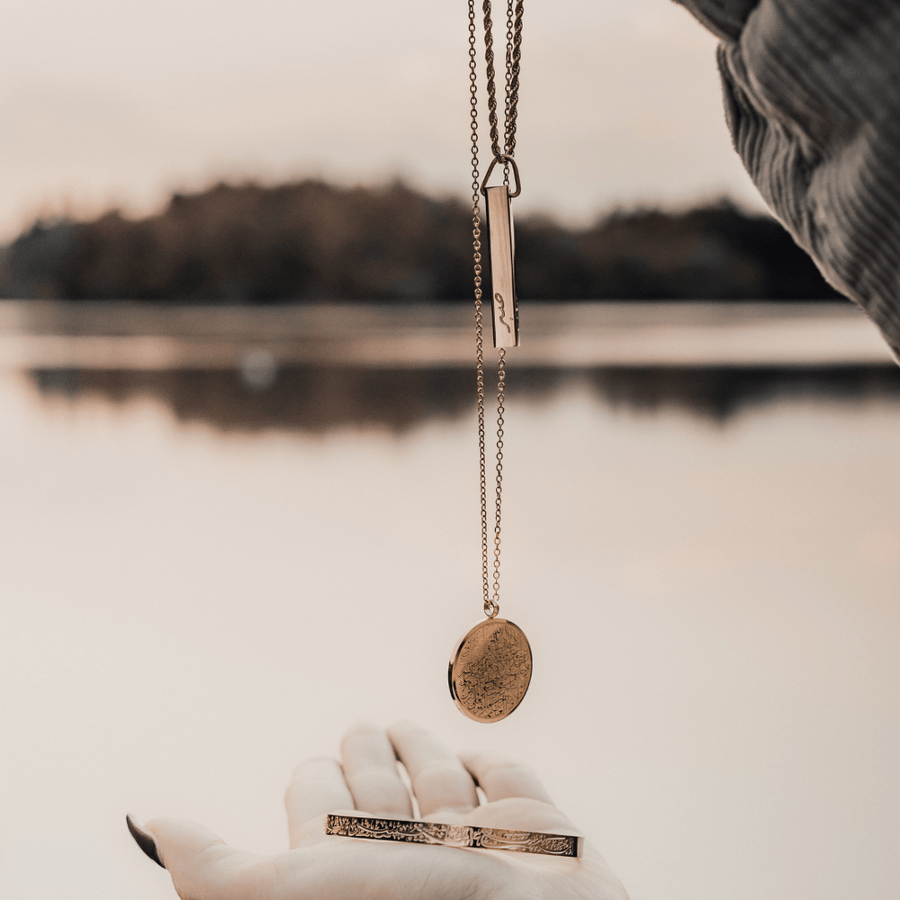 In the photo: Ayatul Kursi Necklace, Mini Core Values Bar Necklace, and "With Hardship Comes Ease" V2 Cuff all in gold.