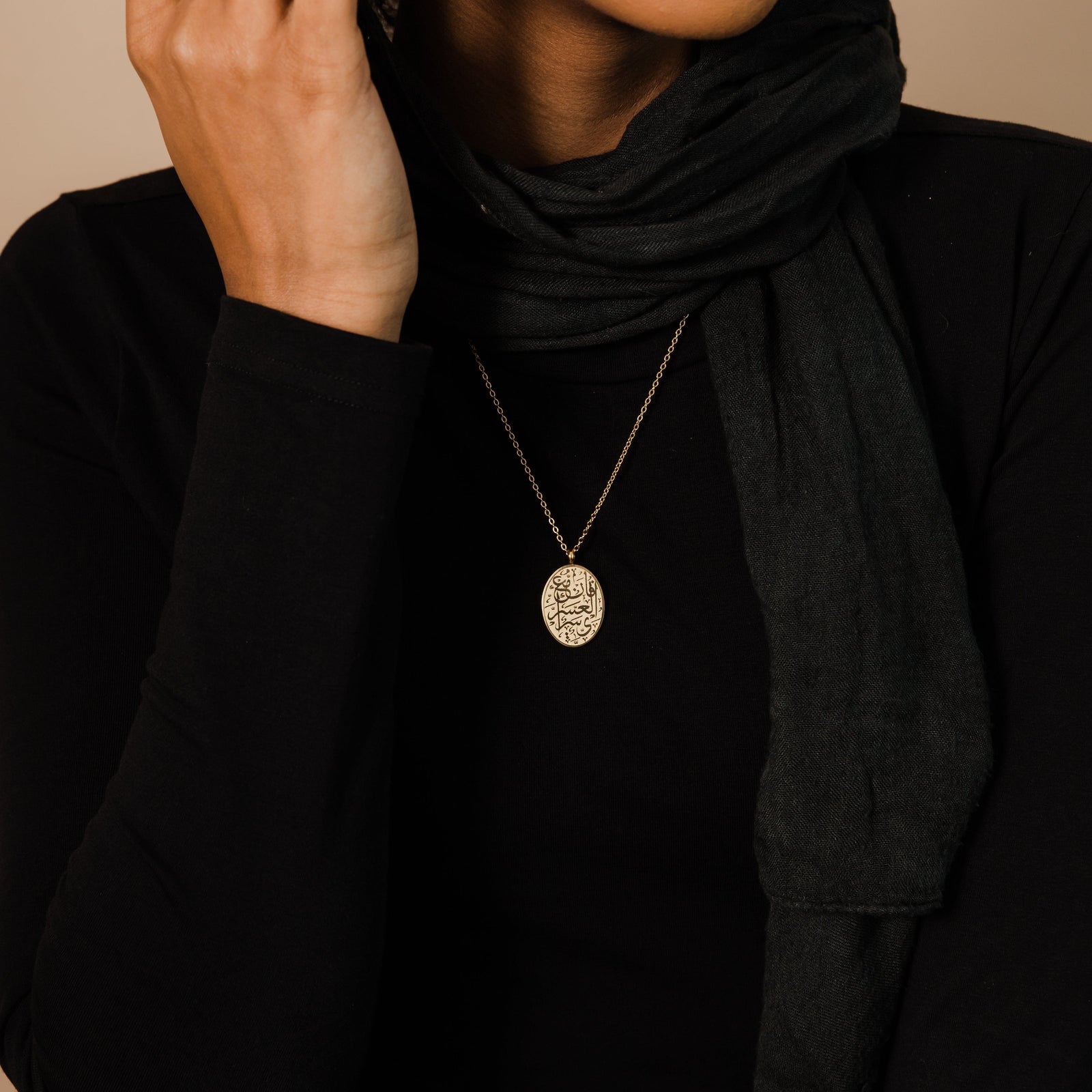 The silver "Verily, with Hardship Comes Ease" Oval Necklace as worn by the model. 