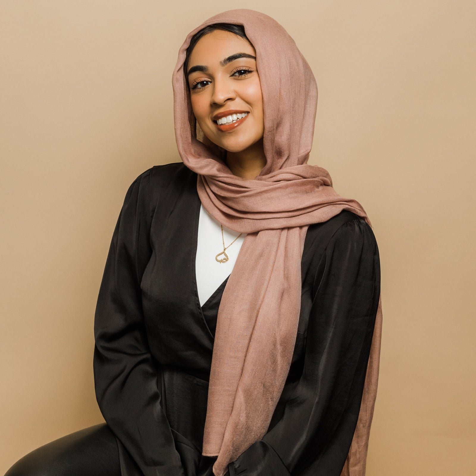 Photo of the model smiling to the camera, the model is wearing the gold Love Heart Calligraphy Necklace.