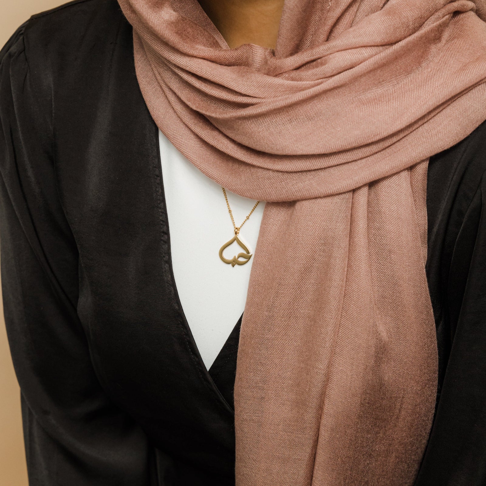 The gold Love Heart Calligraphy Necklace as worn by the model.