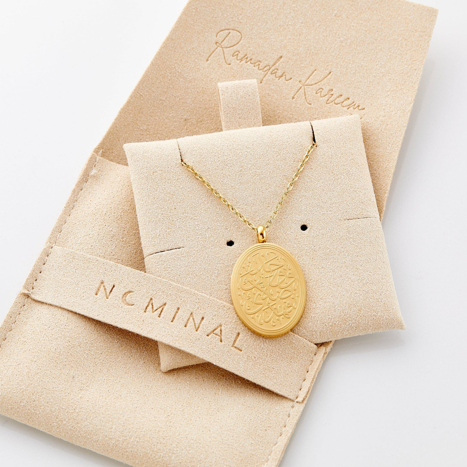 The gold Guidance Calligraphy Necklace displayed on the Nominal packaging.