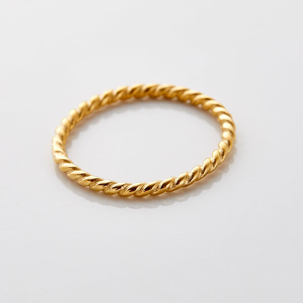 Gold twist ring featuring a delicate rope-like design with a polished finish, displayed flat on a white surface.