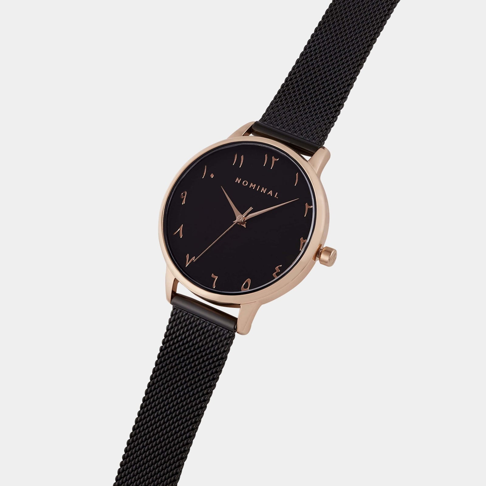 Close-up of a black mesh watch with black background and rose gold details, with minimalist Arabic numerals against a neutral background. 