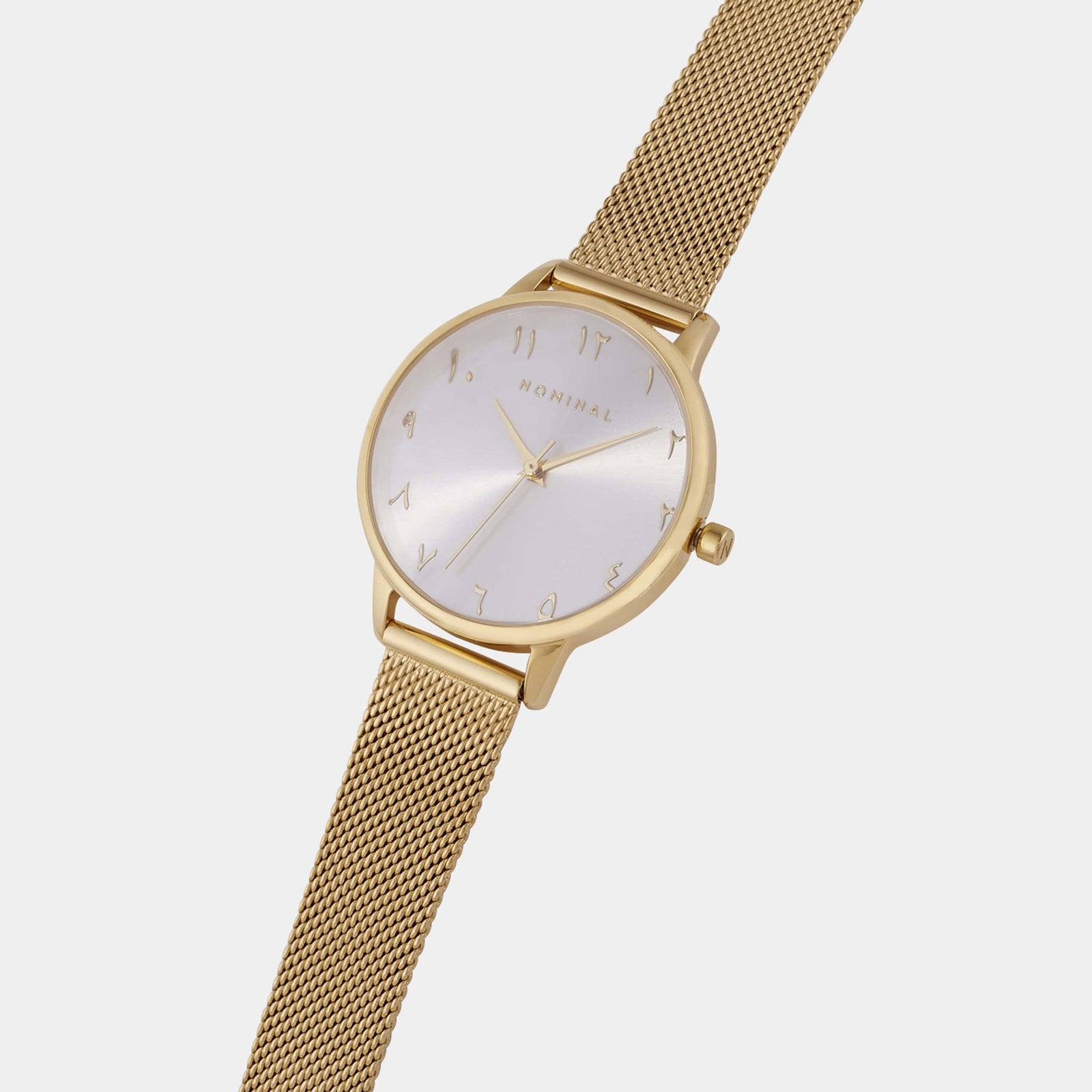 Gold mesh strap watch with white background and gold details, with minimalist Arabic numerals against a neutral background.