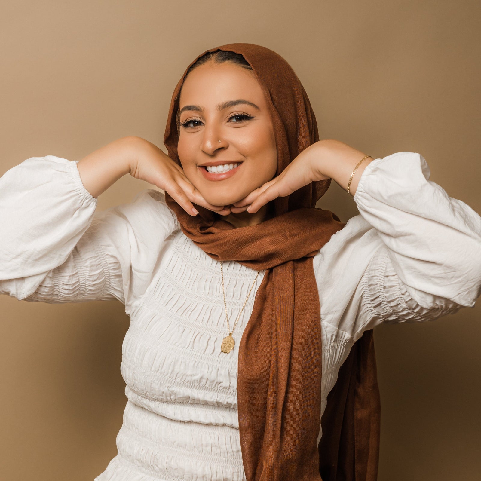 Photo of the model smiling to the camera. The model is wearing the gold Guidance Calligraphy Necklace.
