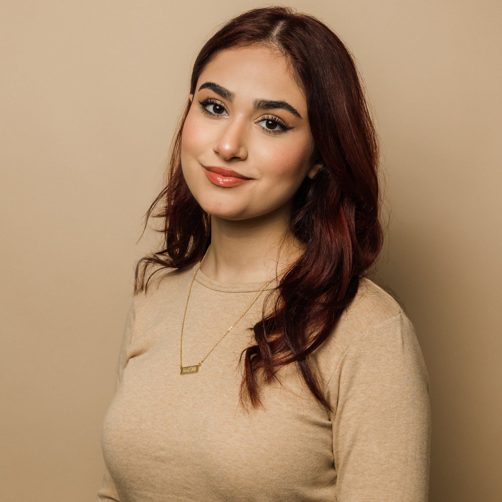 Photo of the model smiling to the camera. The model is wearing the gold Shahada Bar Necklace .